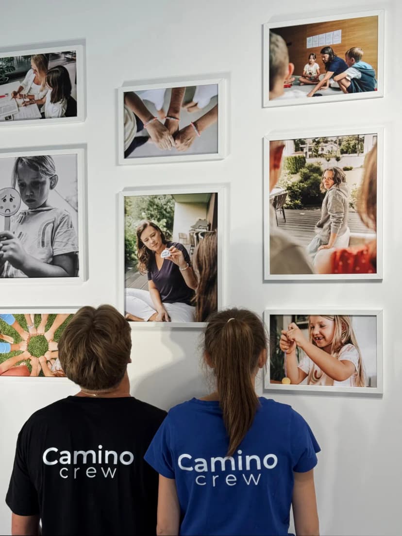 Camino staff wearing matching t-shirts looking at their new gallery wall with multiple picture frames