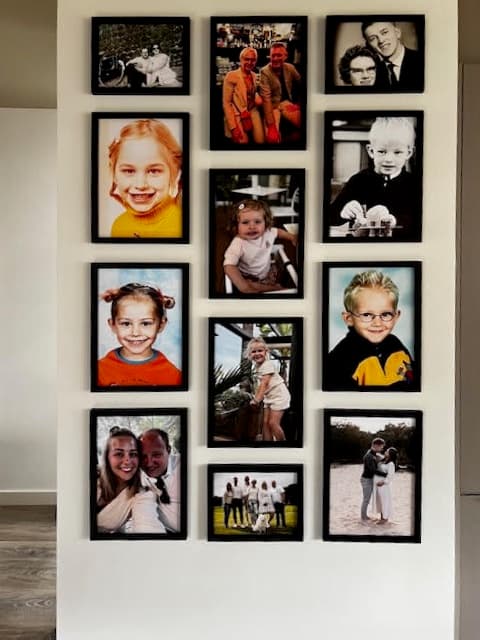Close-up of a family photo gallery wall with black frames